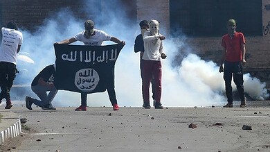 Protesters holding ISIS flag amid tear gas during demonstration.