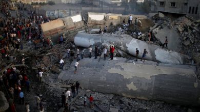 Explosion aftermath in Gaza with collapsed infrastructure and people inspecting the damage.