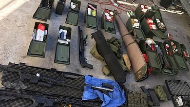 Military equipment and firearms displayed on a table for inspection or sale.