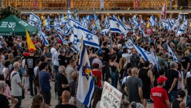 Large crowd of Israelis protesting with flags and banners in support of Netanyahu.