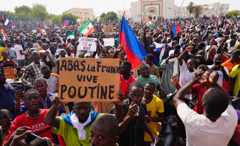 Nigeriens participate in a march called by supporters of coup leader Gen. Abdourahmane Tchiani in Niamey, Niger, Sunday, July 30, 2023. The sign reads: "Down with France, long live Putin