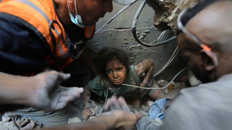 Palestinians try to pull a young girl out of the rubble of a building that was destroyed by Israeli airstrikes in the Jabalia refugee camp, in the northern Gaza Strip