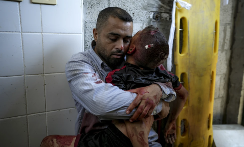 A Palestinian man holds the body of his child killed in the Israeli bombardment of the Gaza Strip, at a hospital morgue in Deir al-Balah, Tuesday, July 9, 2024.