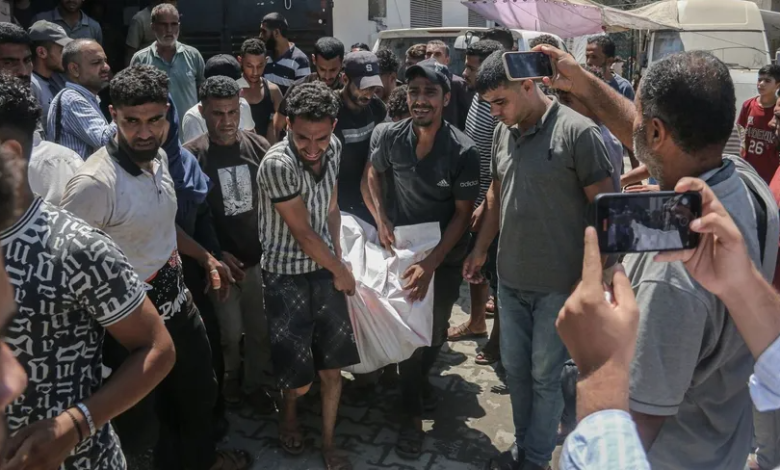 Palestinians carry the body of a victim near Al-Aqsa Martyrs Hospital following an Israeli airstrike on Deir al-Balah in the Gaza Strip, August 20, 2024