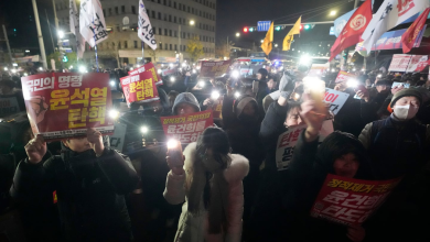 Protesters hold up signs reading President Yoon Suk-yeol step down against the backdrop of martial law at the National Assembly in Seoul, December 4, 2024.