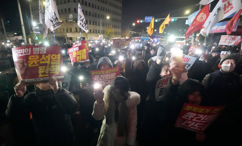 Protesters hold up signs reading President Yoon Suk-yeol step down against the backdrop of martial law at the National Assembly in Seoul, December 4, 2024.