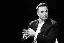 Male speaker in a suit during a discussion or interview on stage.