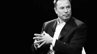 Male speaker in a suit during a discussion or interview on stage.