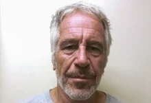 Man with gray hair and beard, looking directly at the camera, neutral expression.