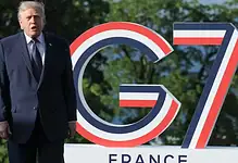 Donald Trump speaking at G7 summit with G7 logo in background.